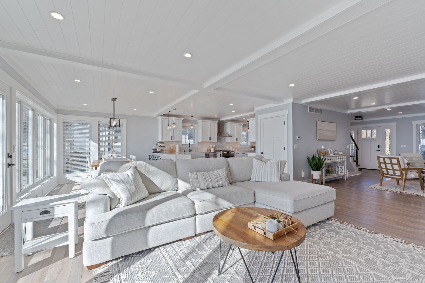Open living room with white sectional and wall-to-wall lake windows