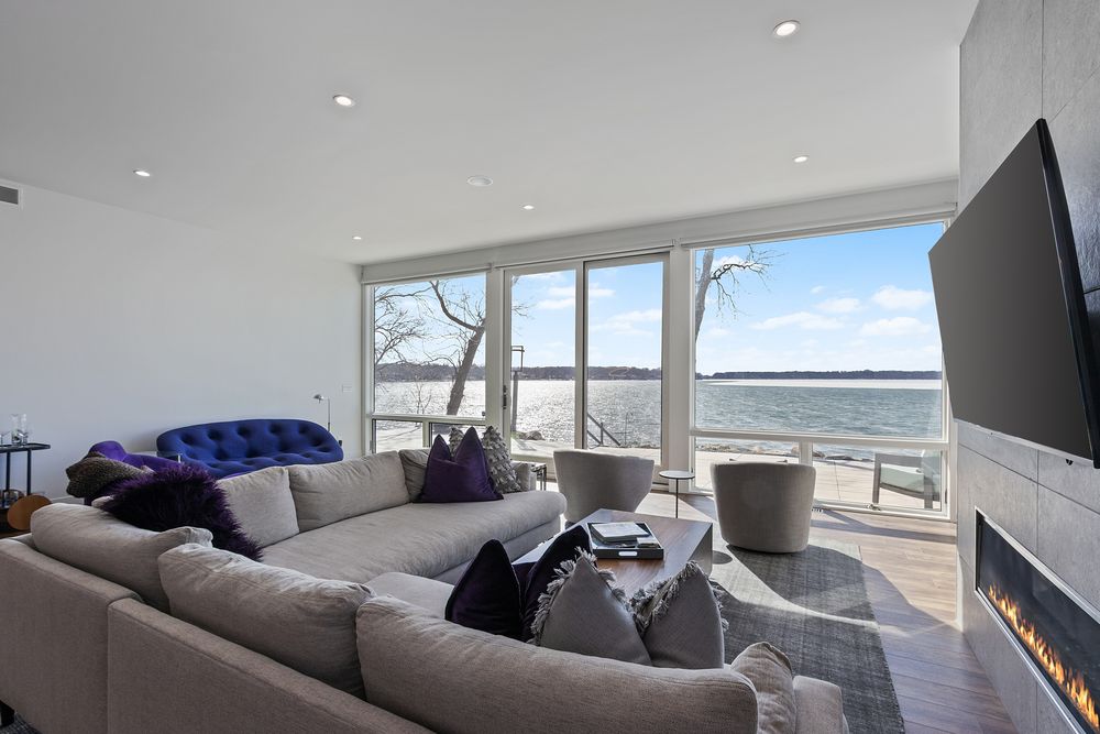 Living room with sectional, fireplace and a wall of lake-view windows