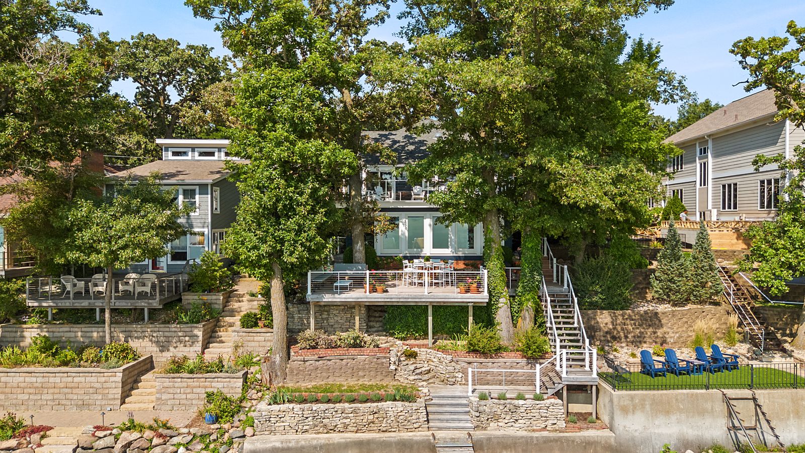 Drone view of a lakefront home with terraced yard, stairs and dock