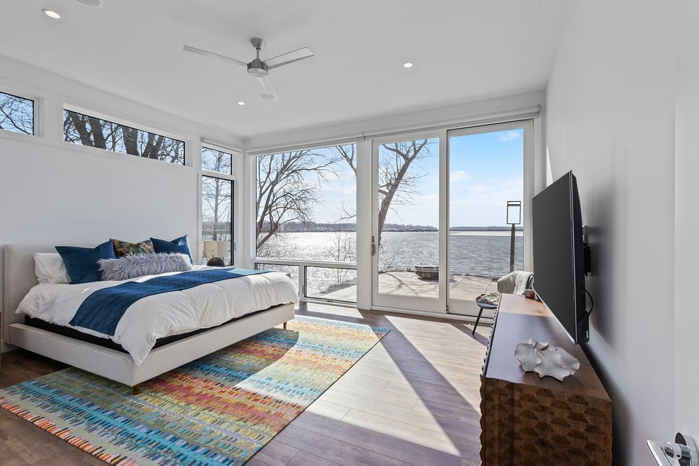 Primary bedroom with floor-to-ceiling windows facing the lake